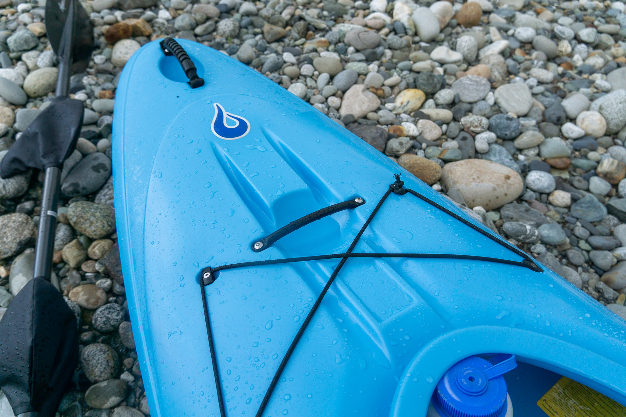 the bow of the remix xp kayak on a river cobble shore, showing the bungee corded section and handle