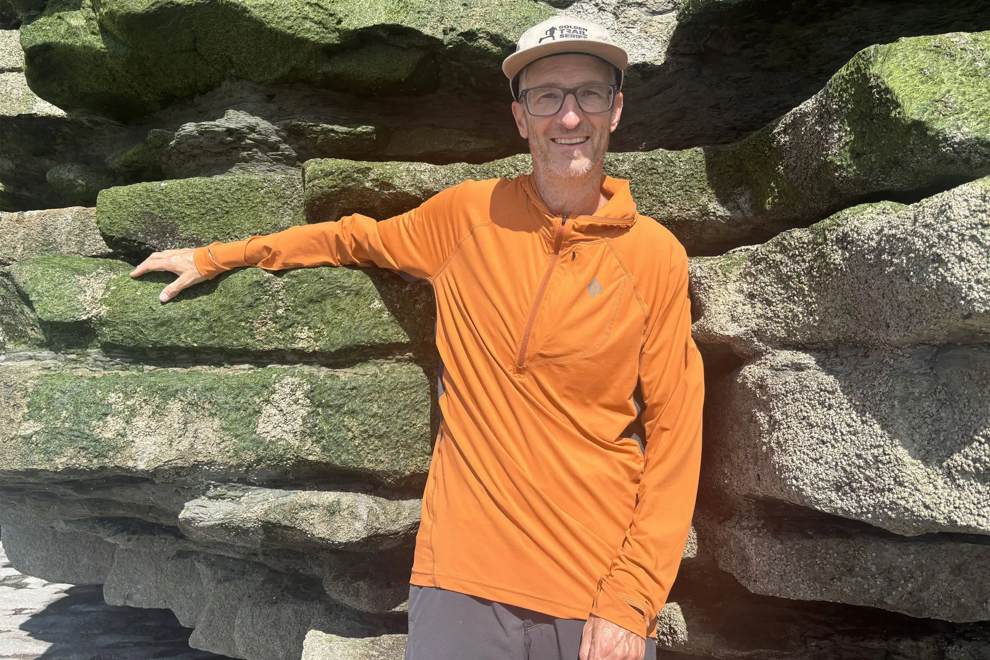 Man in Alpenglow Pro Hoody leaning on a rock