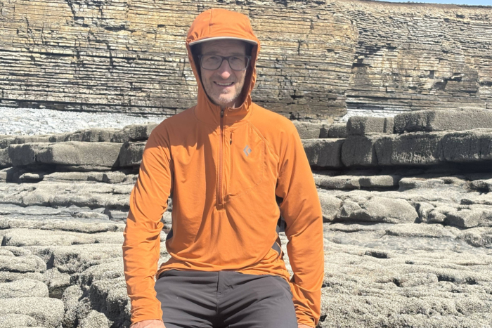 Man wearing Black Diamond Alpenglow Pro Hoody sitting on a rock