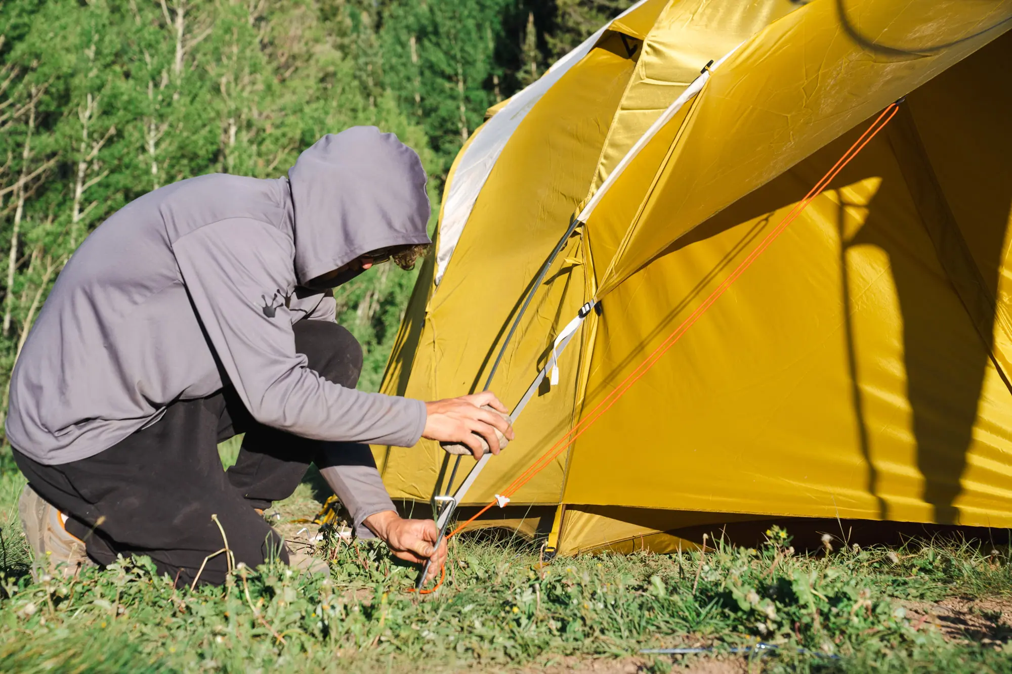 a camper setting a tent stake on the base camp 6 tent