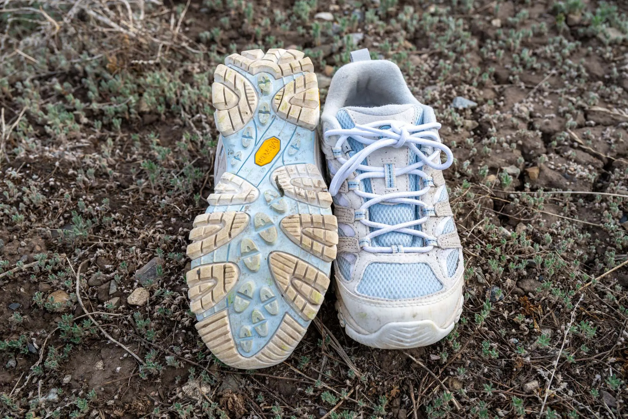 Moab 3 on rocky ground, one showing sole, the other upright