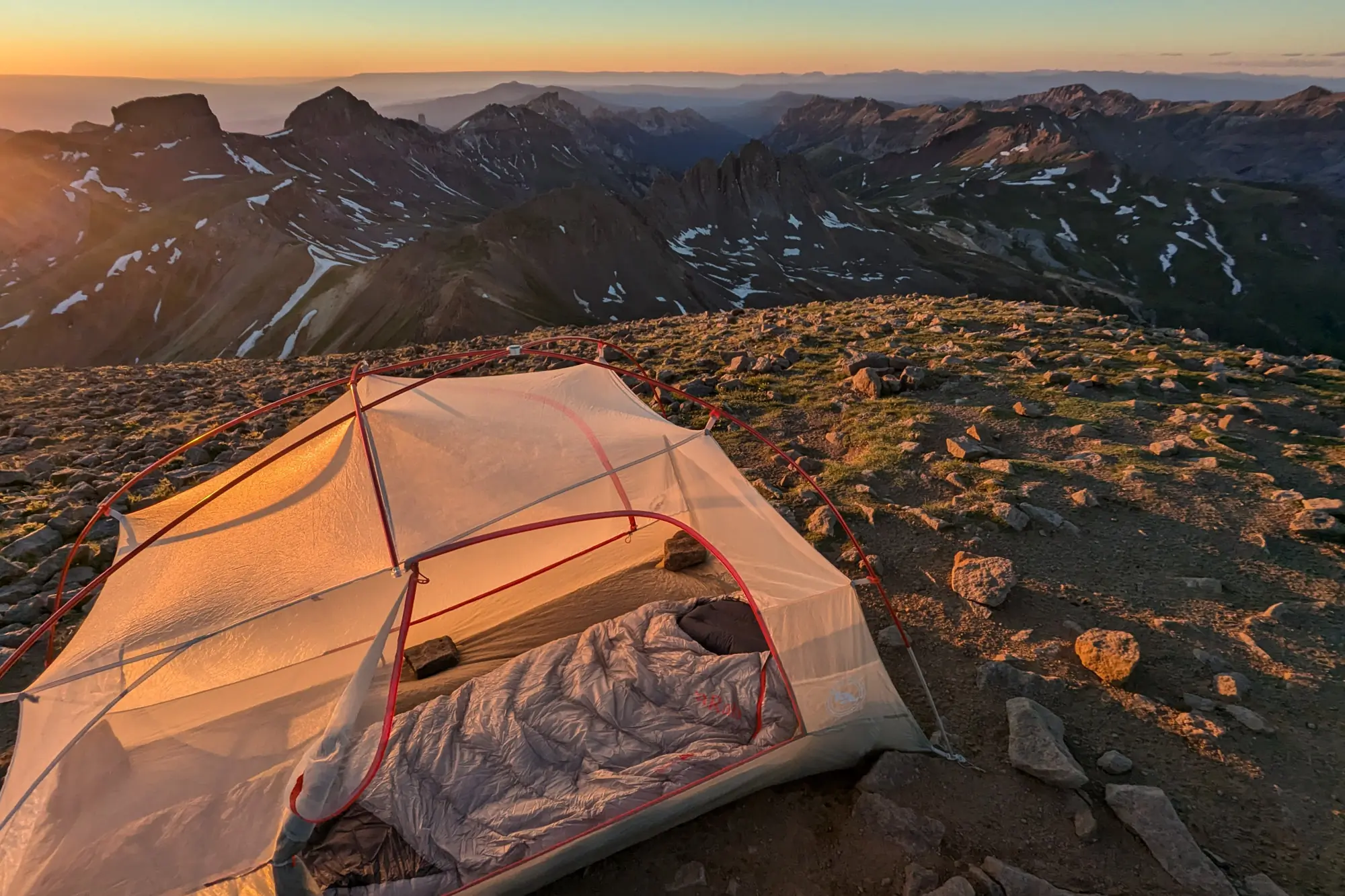 the mythic ultra sleeping bag inside of a tent atop wetterhorn peak in colorado with the sun setting