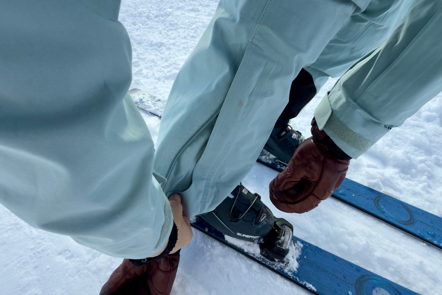 Close-up of a skier adjusting their pant over a ski boot