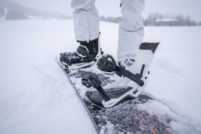 Close-up of snowboard boots strapped into white Jones Mercury FASE snowboard bindings