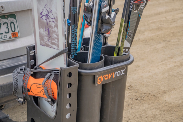 The Gravirax GR-4 rack holds skis, poles, and a snowboard with a boot securely strapped in place.