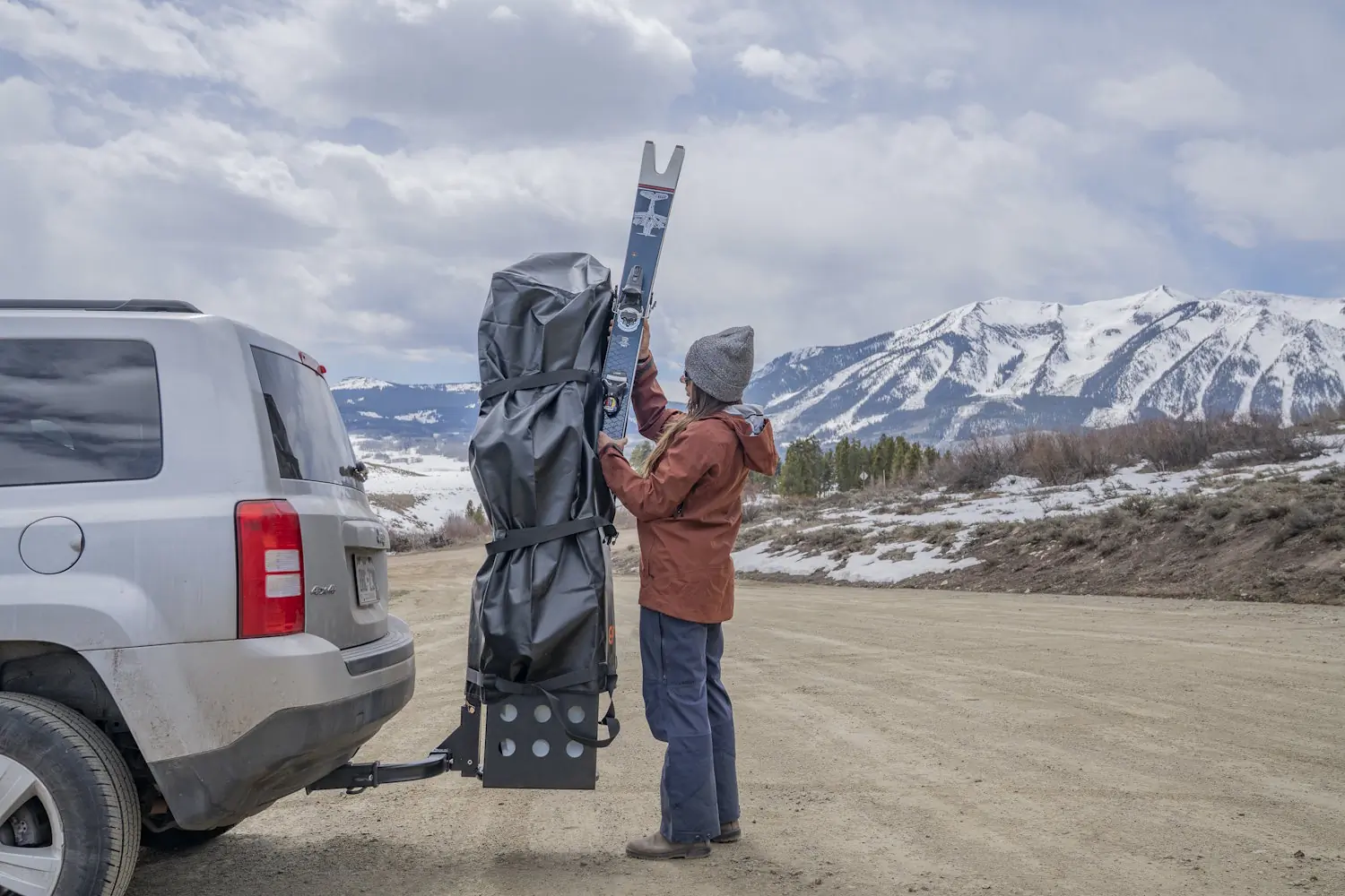 Person loading skis into a Gravirax GR-4 Hitch Mounted Ski Rack