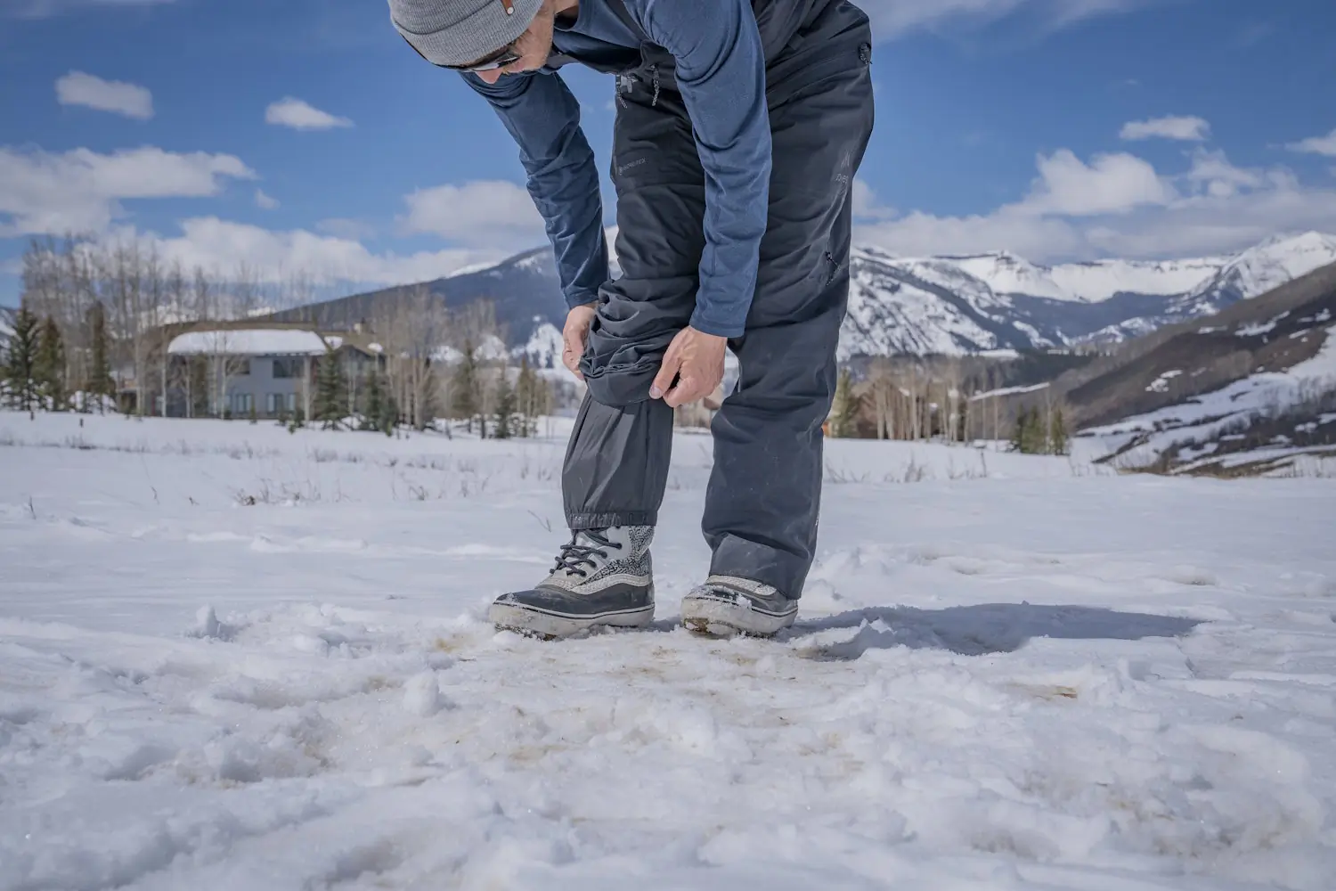 Person adjusting the internal snow gaiter of their GORE-TEX bib pants over winter boots