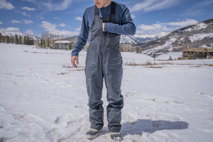 Man wearing Jones Shralpinist Recycled GORE-TEX ePE Bibs adjusting chest pocket
