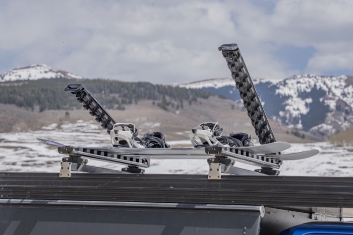 Two snowboards rest in an open Kuat Grip 6 Ski/Snowboard Rack mounted on a vehicle rooftop