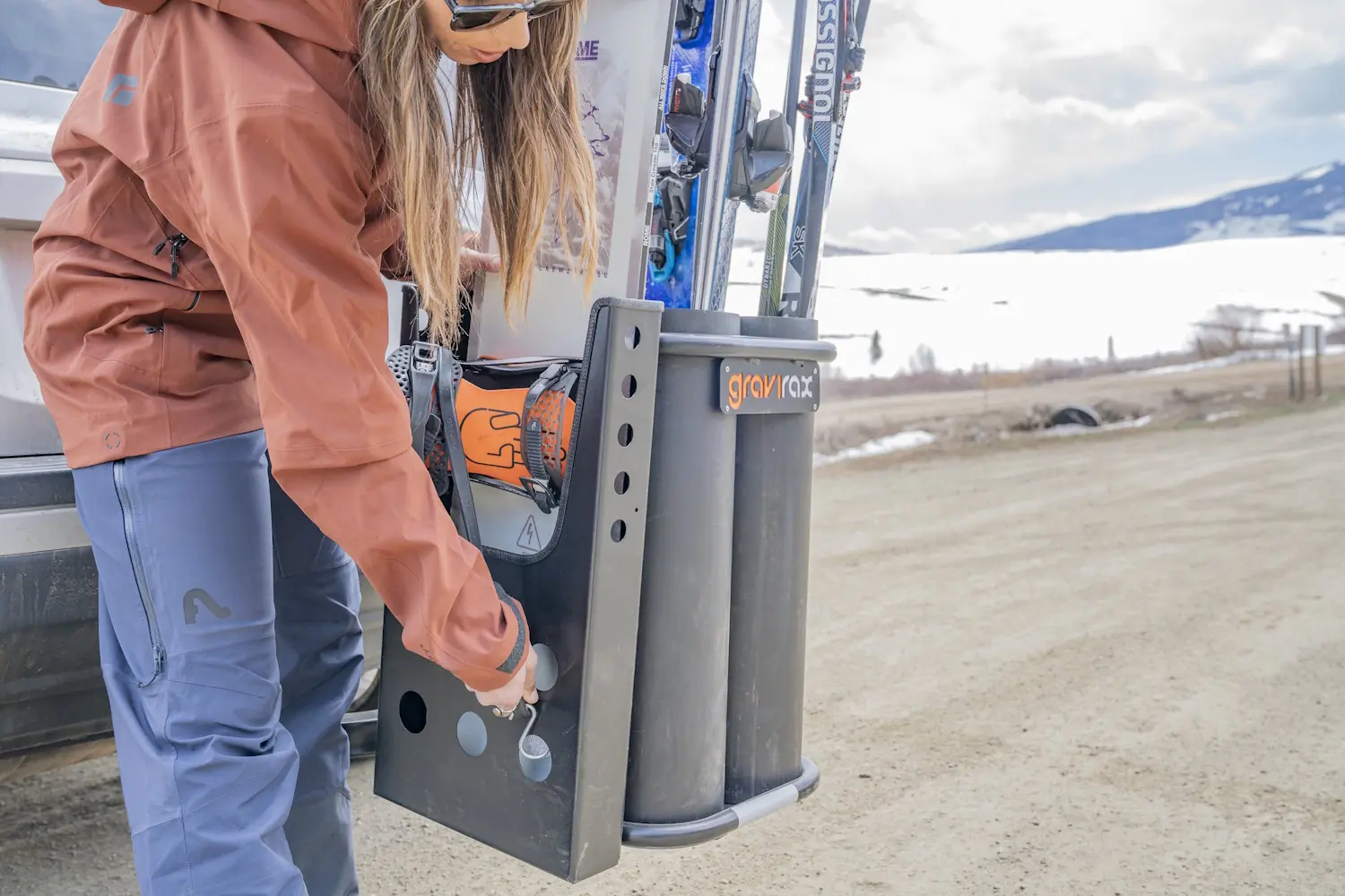 Person loading skis into a Gravirax GR-4 Hitch Mounted Ski Rack.