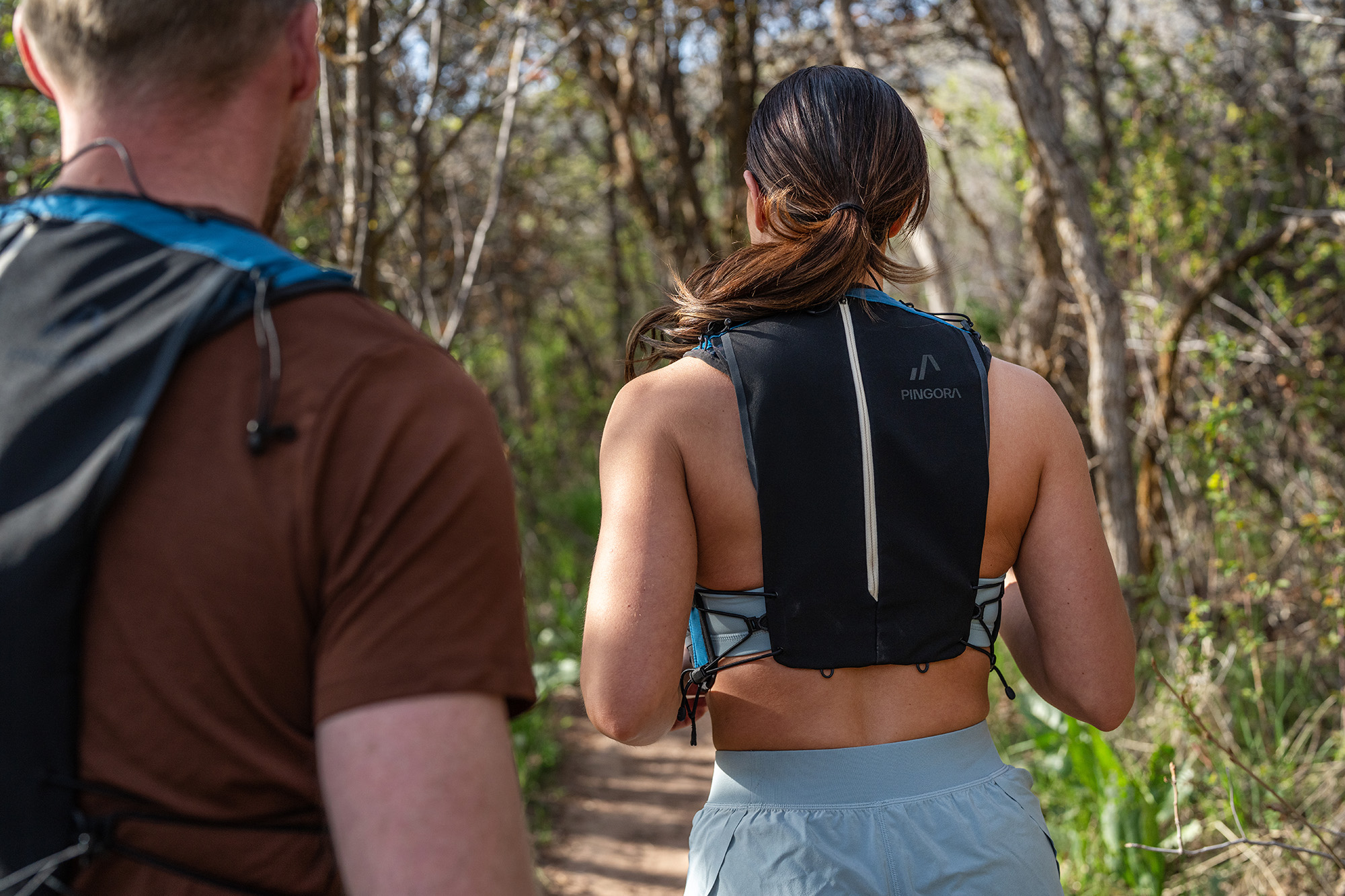 man and woman from behind running on trail