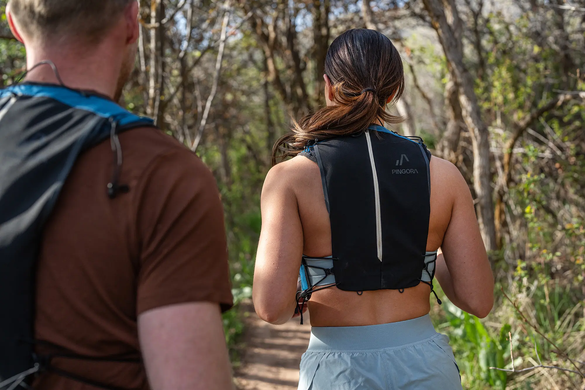 man and woman from behind running on trail