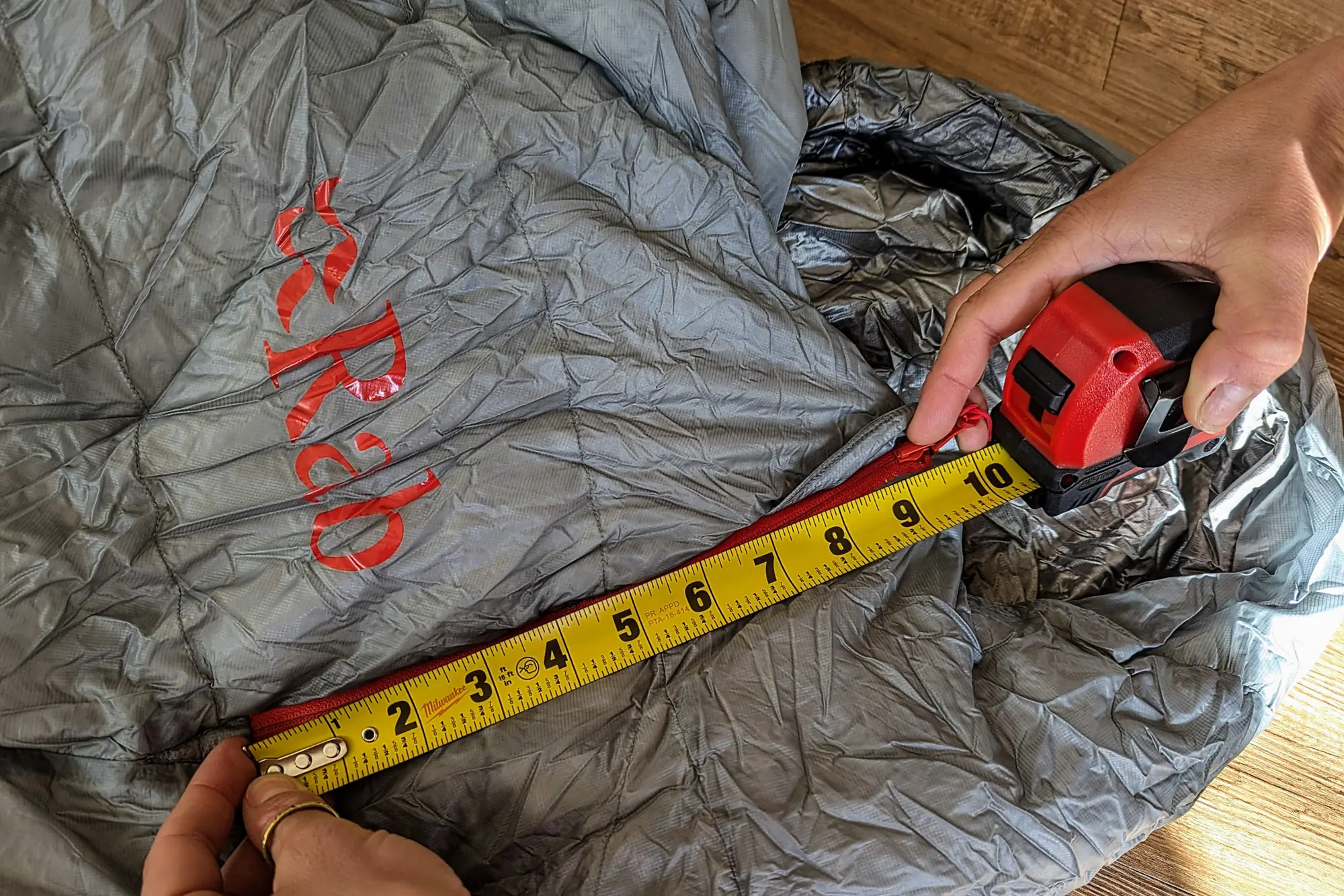 the author measures the entrance zipper on the sleeping bag, showing that it is only 9.5" long