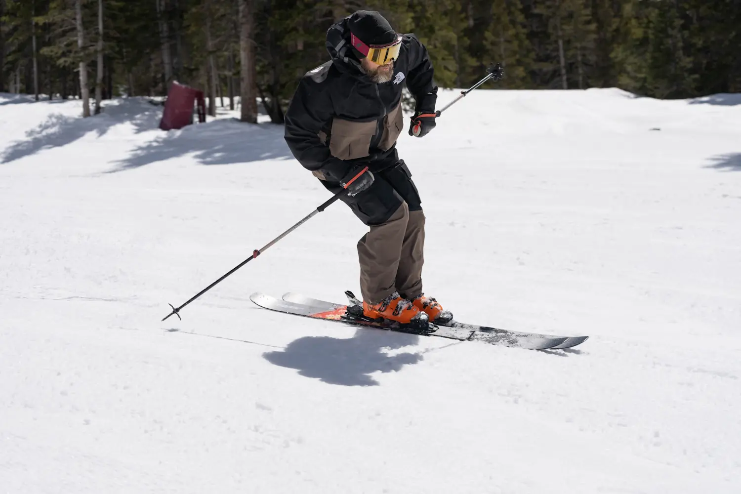 Skier in action wearing Tecnica Mach1 LV 130 boots on a snowy slope, demonstrating aggressive forward stance.