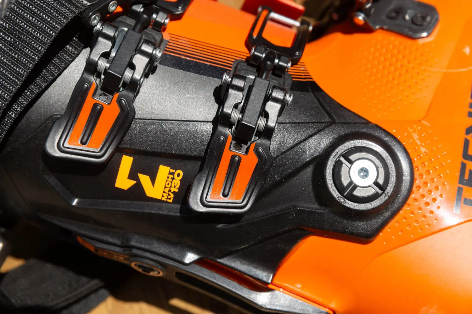 Close-up of Tecnica Mach 1 Men’s LV 130 ski boot buckles and logo.