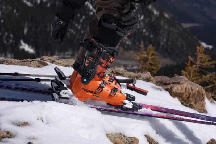 Tecnica Mach 1 Men’s LV 130 ski boots clipped into bindings on snow.