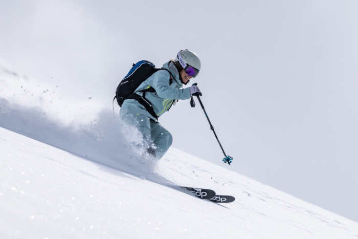 A skier wearing Columbia Platinum Peak II pants carves through deep powder on a snowy mountain slope