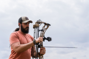 A man adjusting a compound bow outdoors