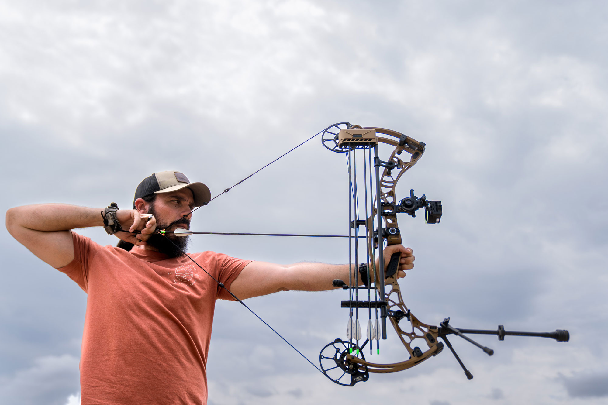 A man aiming a compound bow outdoors