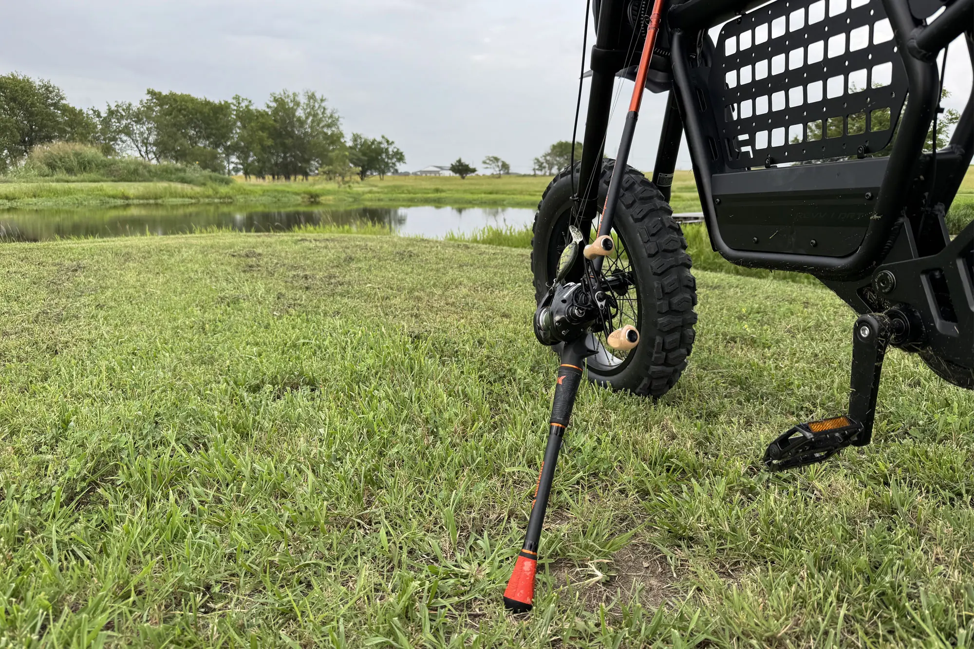 Close-up of a fishing rod resting against an off-road electric bike
