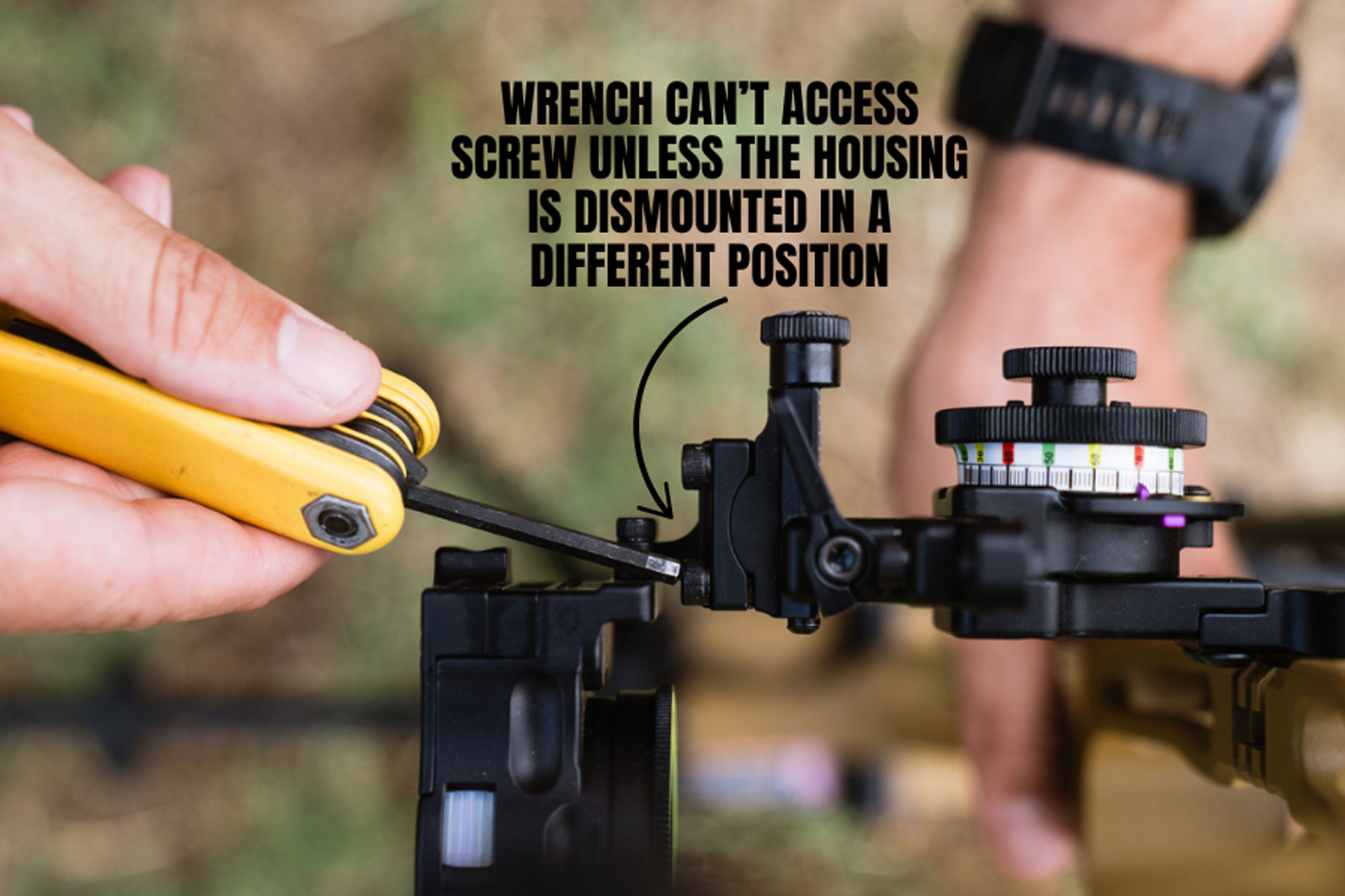 Close-up of a person using a wrench on a bow sight