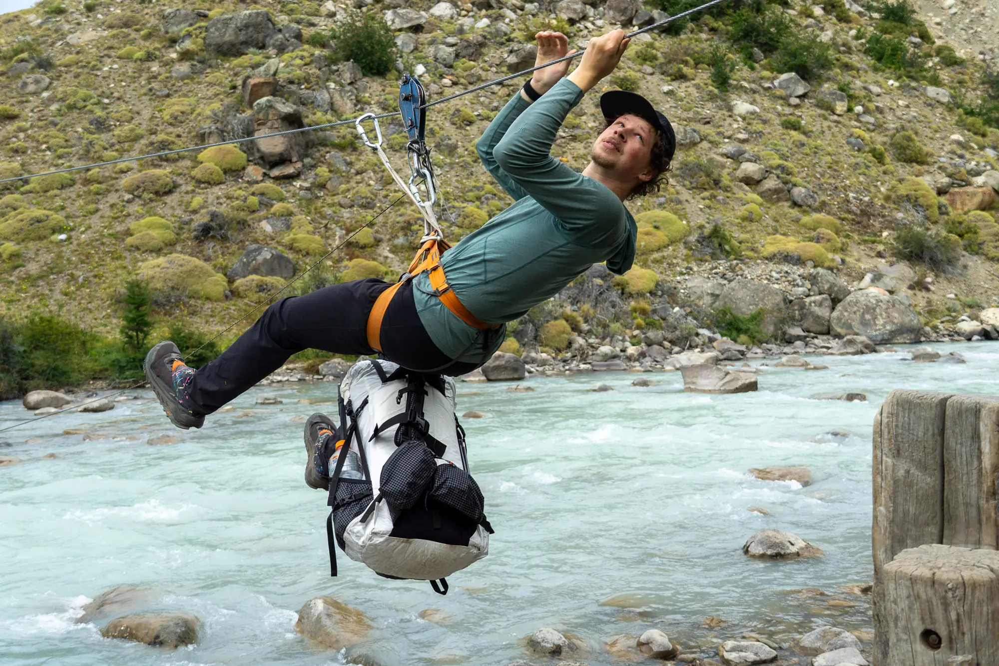 the author crosses a patagonian river via a tyrolean traverse, with the hyperlite southwest pack suspended below him