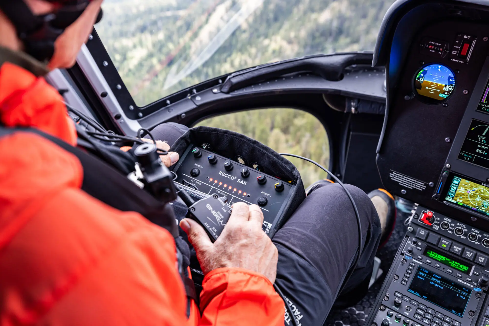 A RECCO operator scans terrain from inside a helicopter