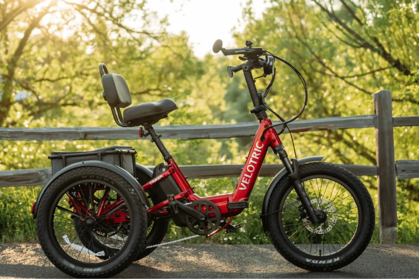 Red three-wheeled bike in front of a fence in a park