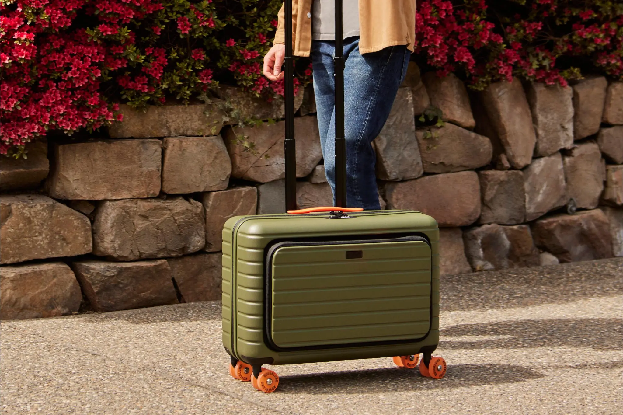 Close up of green suitcase being wheeled down a street 