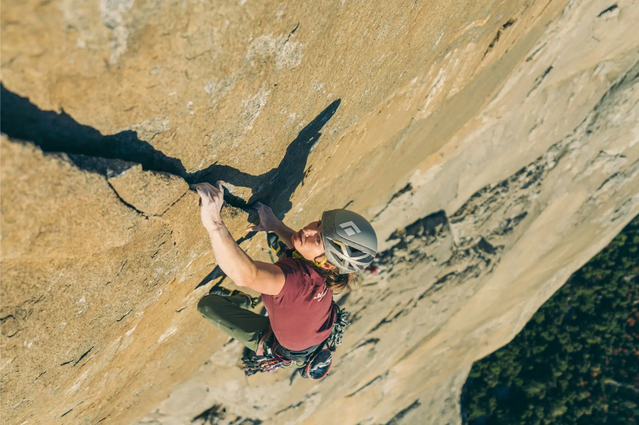 Babsi Zangerl climbs a sheer rock face while looking up 