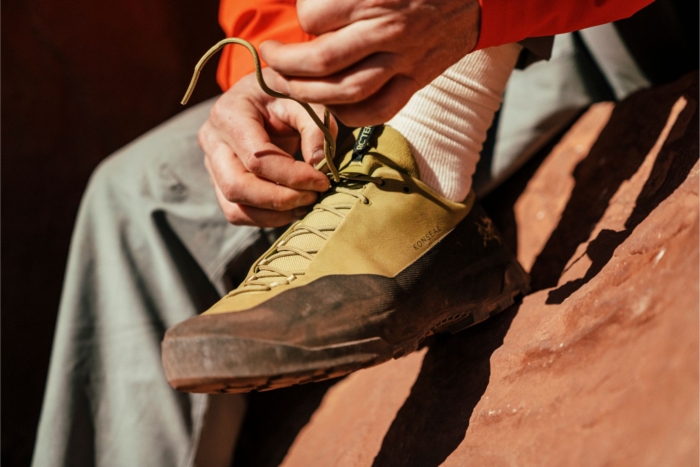 Man sitting on rock laces up Konseal shoe