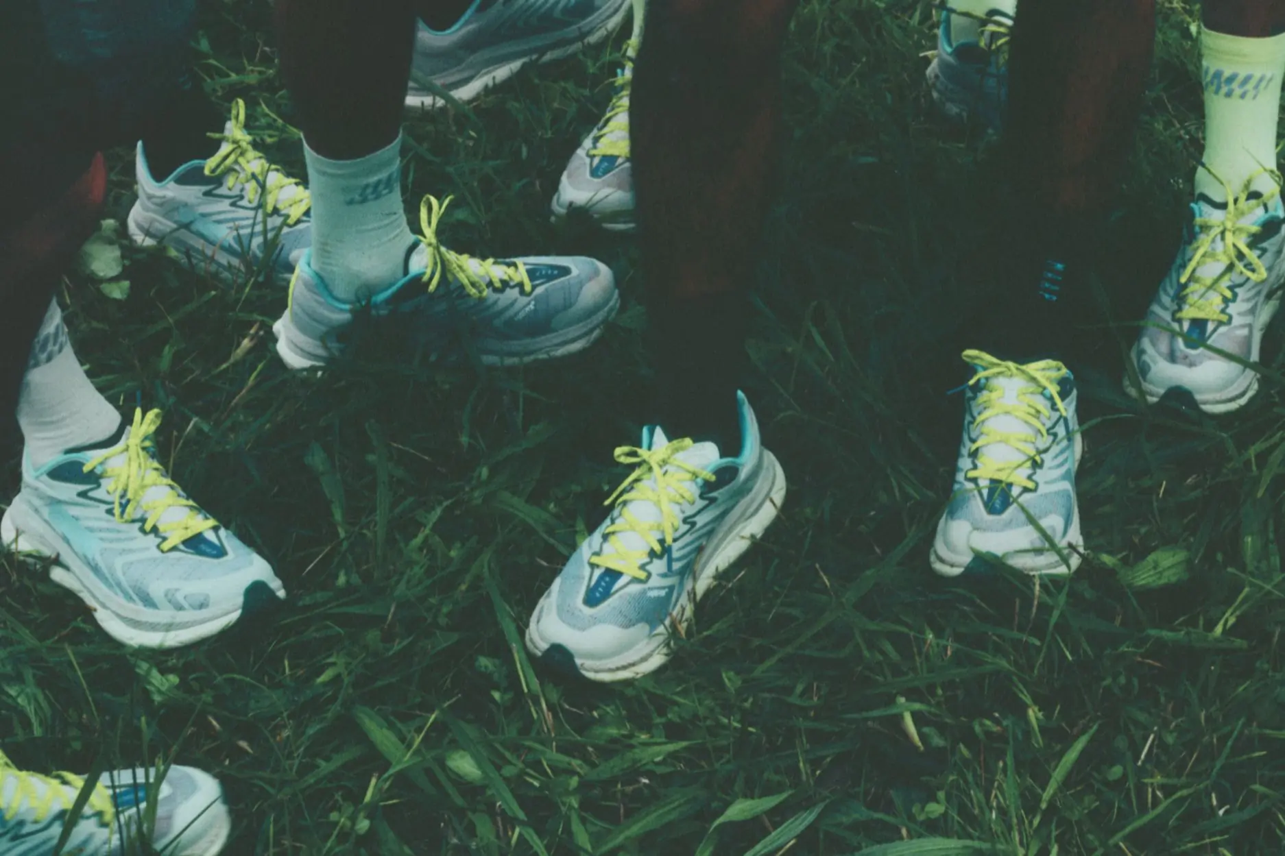 Group of people shown from the knees down wearing sneakers with bright neon laces 