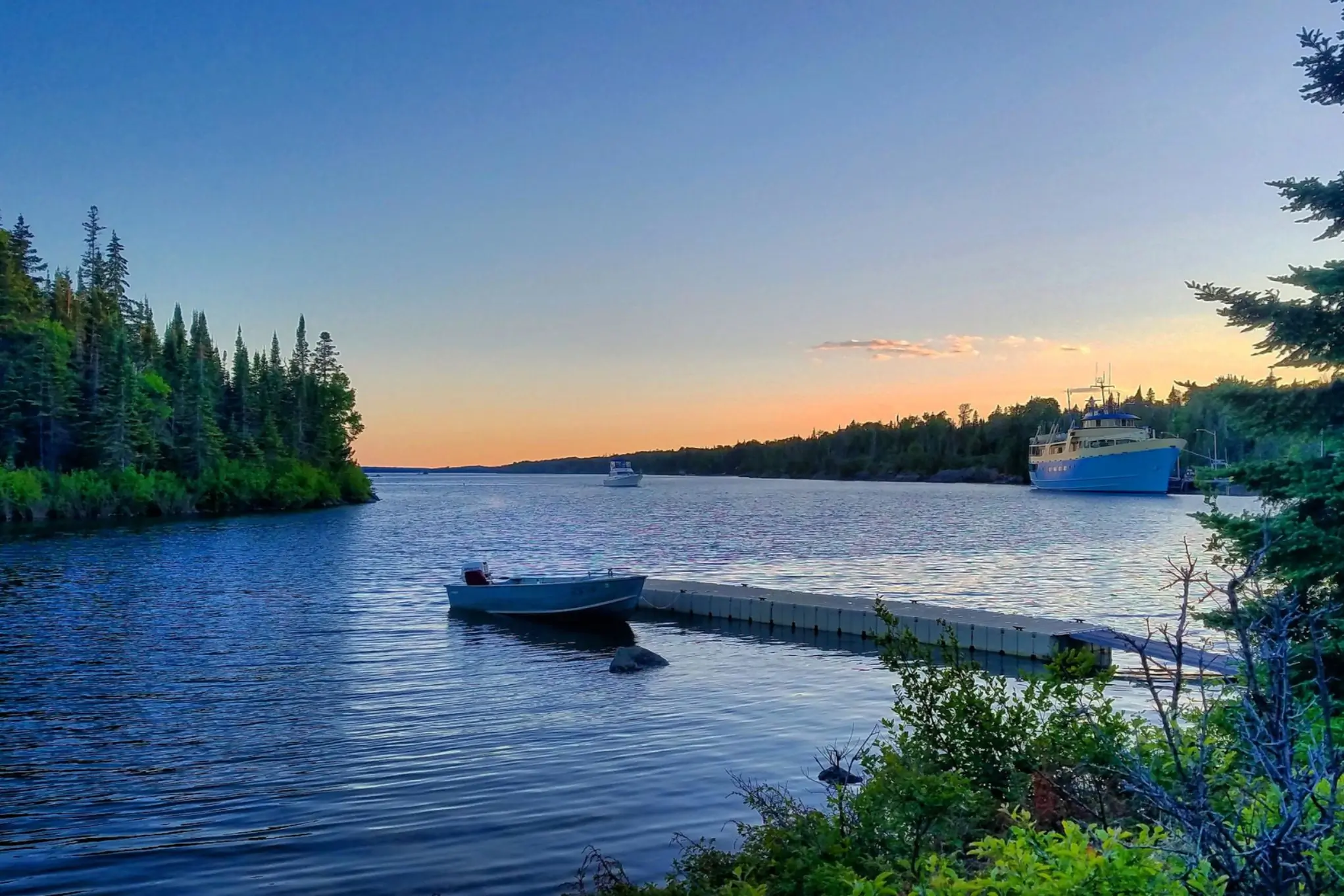 A boat docked at sunset with a ferry in the background