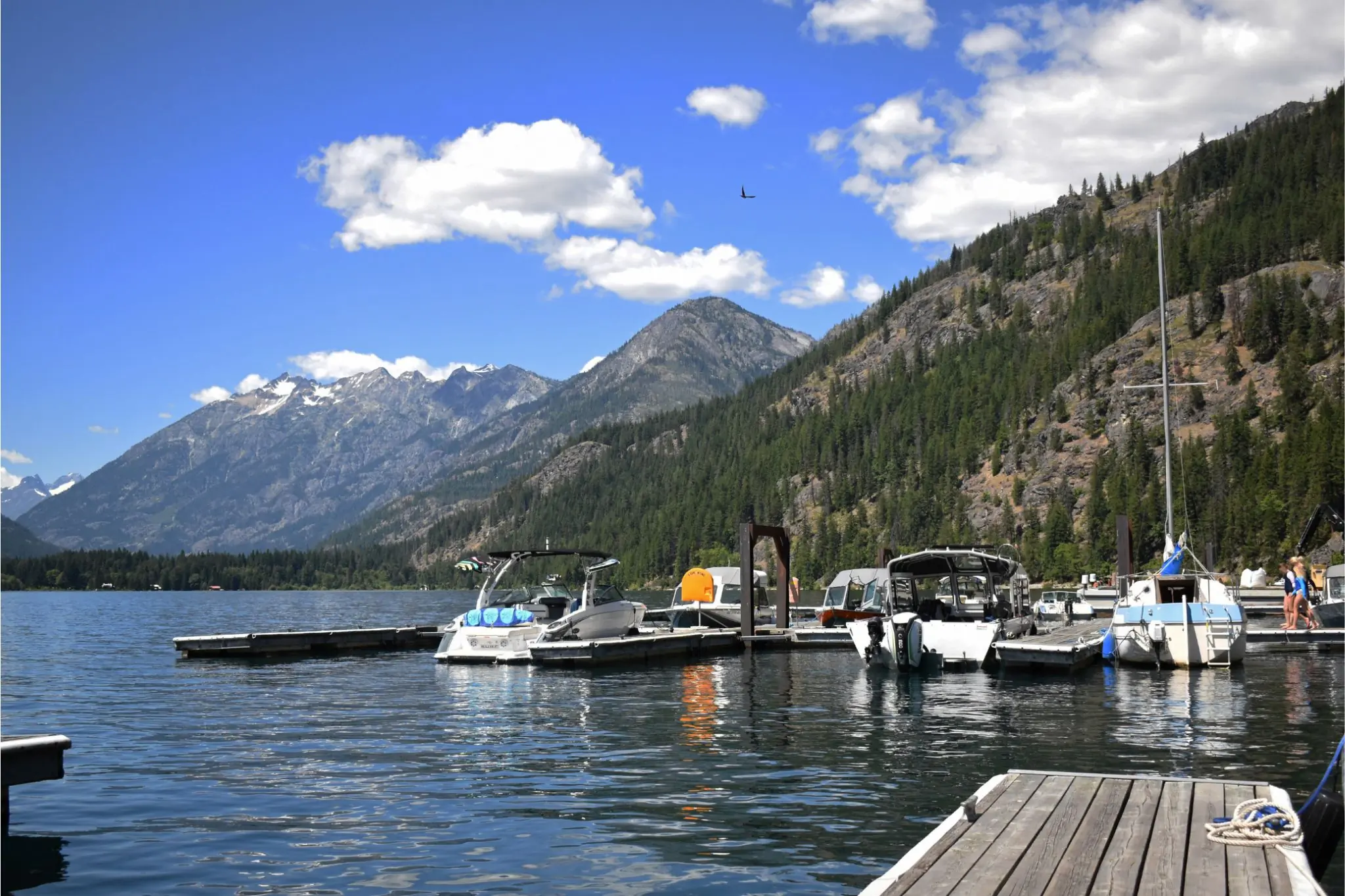 Multiple boats docked in the water with view of mountains in the background