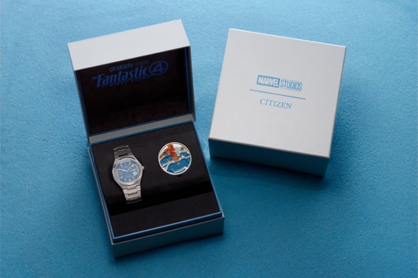 Watch and commemorative coin in open box on blue surface 