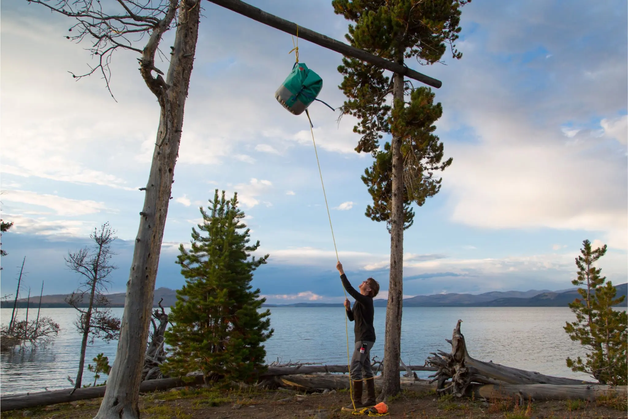 Man in front of lake hangs food on large pole