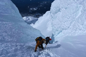 Two climbers hike up a steep amount of snow