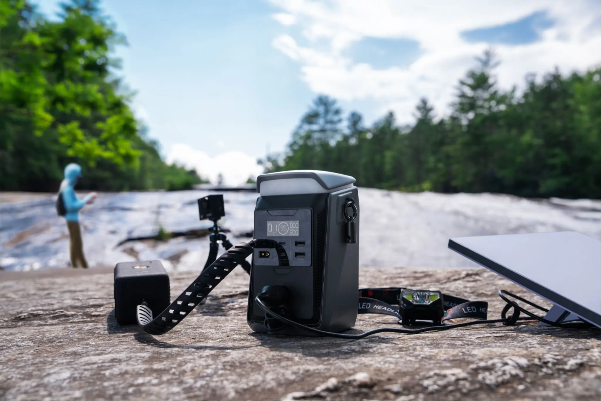 Power station charing multiple devices on a rock in front of a river