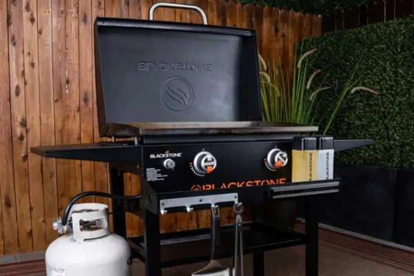 Blackstone Griddle set up a propane tank in front of a wooden wall 