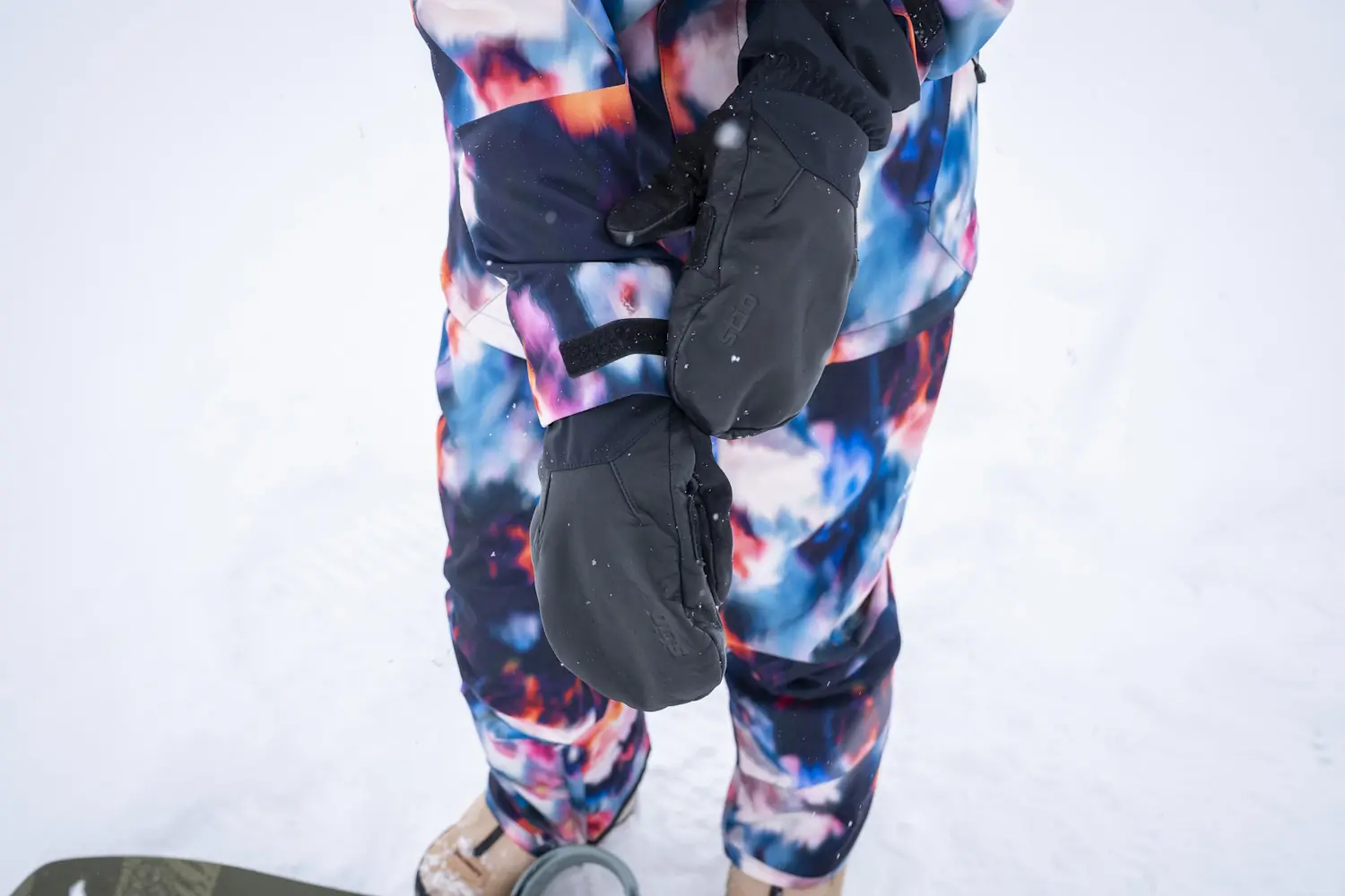 Close-up of a person wearing Stio Objective Insulated Winter Mittens standing in snow