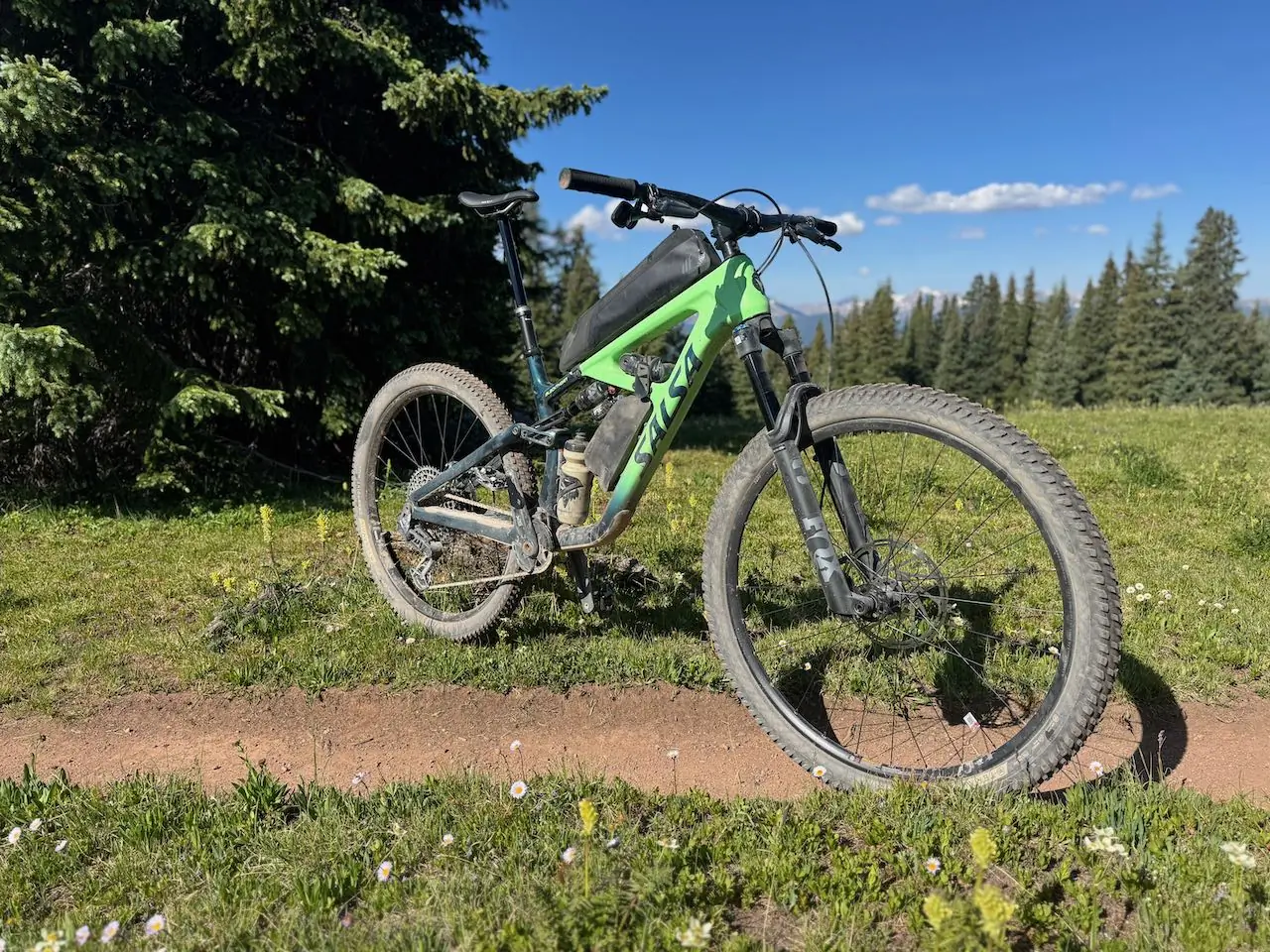Salsa Blackthorn 125 resting near trees with mountain views in the background