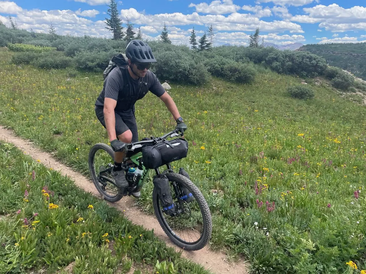 Rider pedaling the Salsa Blackthorn 125 through a colorful wildflower meadow