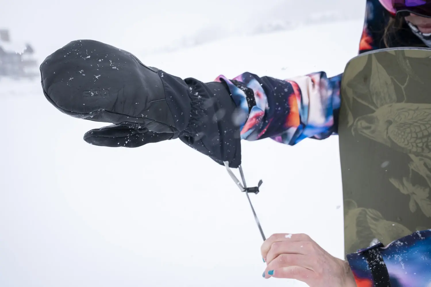 Person tightening Stio Objective Winter Mitten in snow.