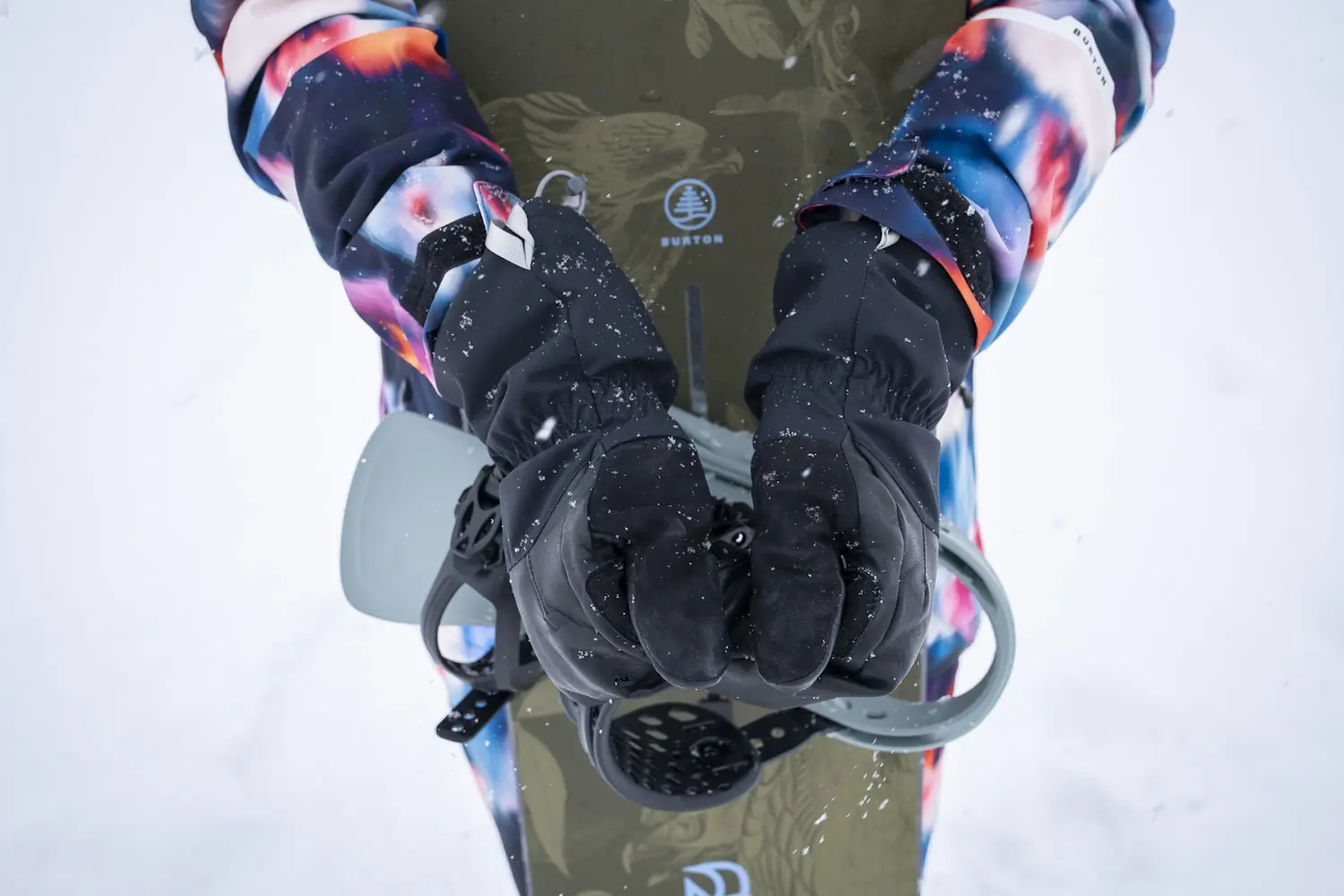 Person wearing Stio Objective Mittens holding snowboard bindings in snow.