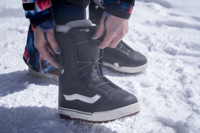 Woman tightening Vans Women's Encore Pro Snowboard Boot in the snow.