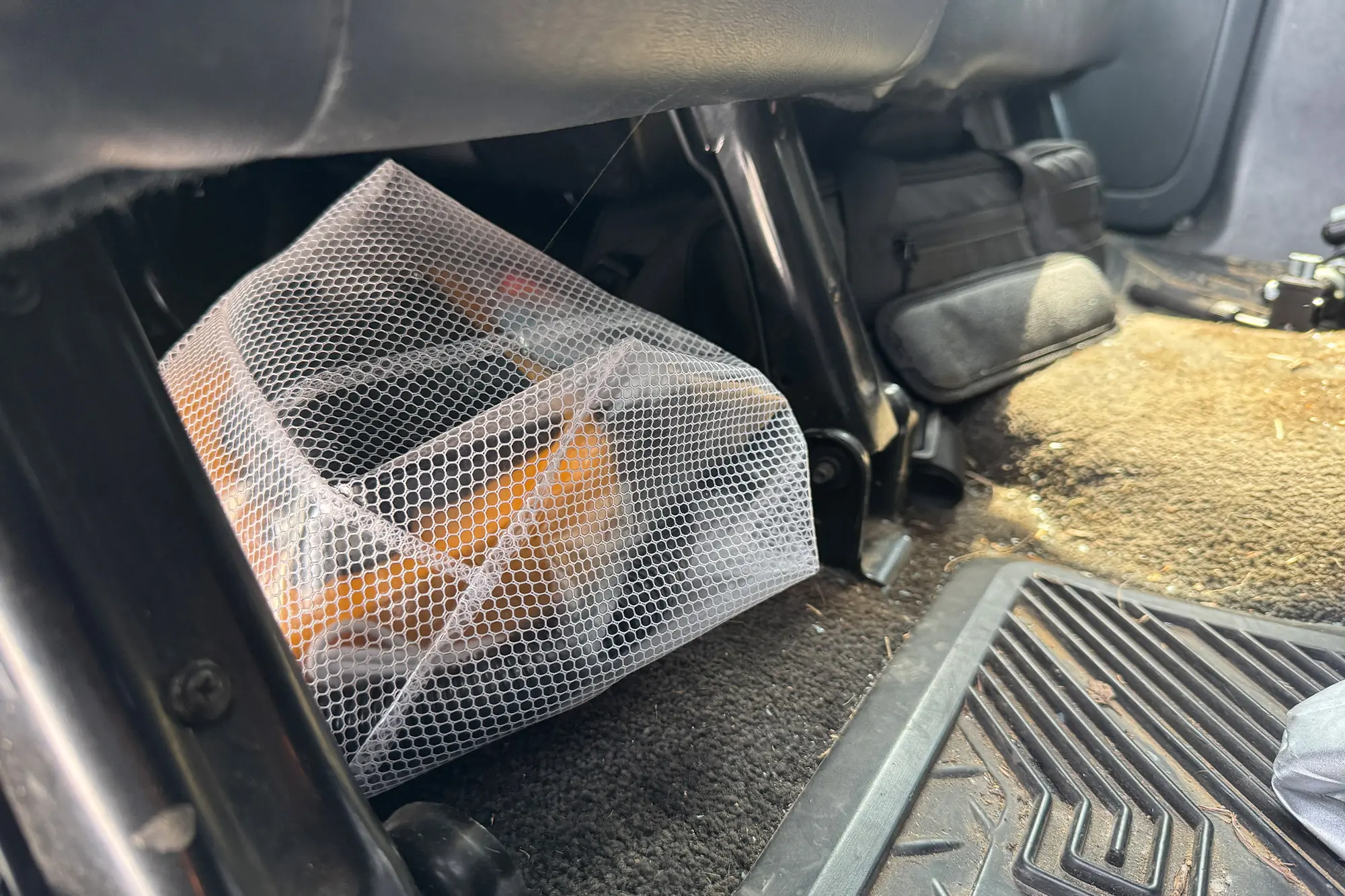 AIRBANK PULSE Pro Electric SUP Air Pump stored in a white mesh bag under a car seat