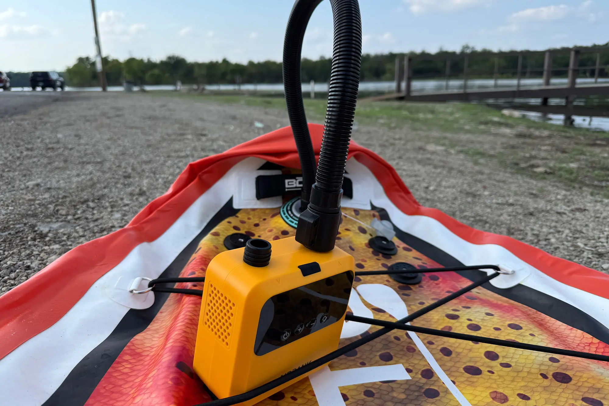AIRBANK PULSE Pro Electric SUP Air Pump connected to an inflatable board on a gravel shore
