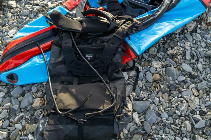 the seek outside unaweep pack disassembled with the frame out sitting beside a blue and red packraft