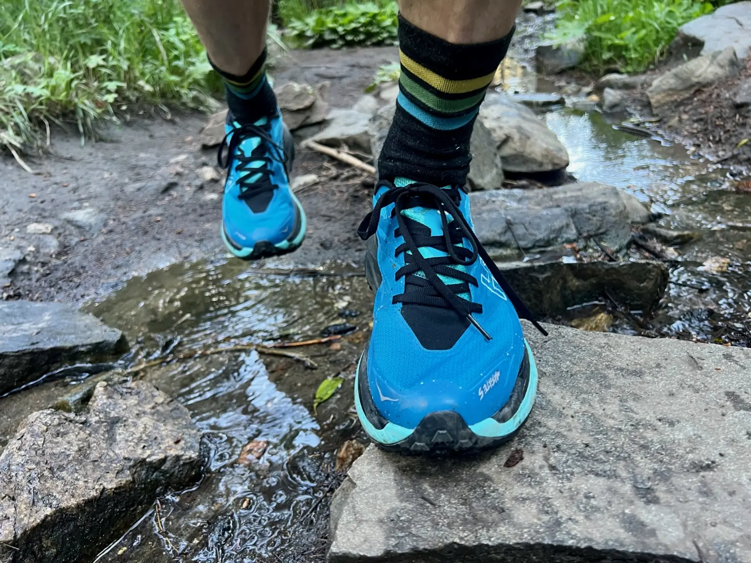 Hoka Mafate 5 in blue on rocks with stream