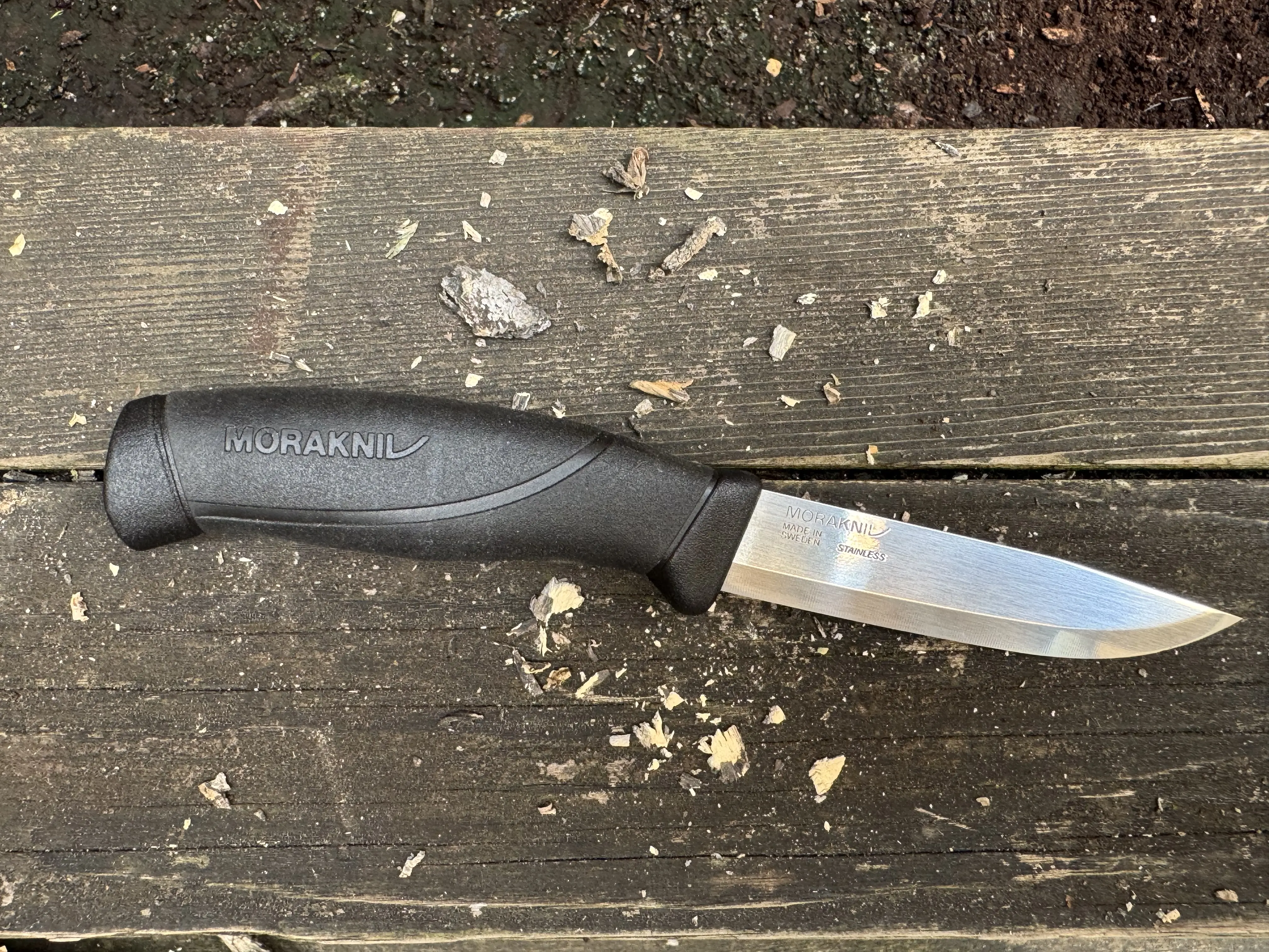 Morakniv Companion knife on a weathered board amidst wood chips